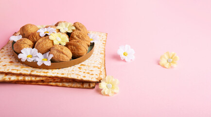 Fototapeta na wymiar Passover Greeting Card with Matzah, Nuts and Spring Flowers on Pink Background.