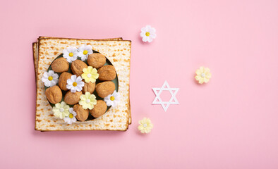 Passover Greeting Card with Matzah, Nuts and Spring Flowers on Pink Background.