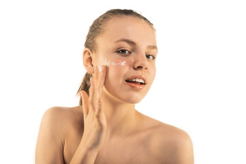 Lovely girl protecting her skin from dryness. Putting moisturizing cream on her face