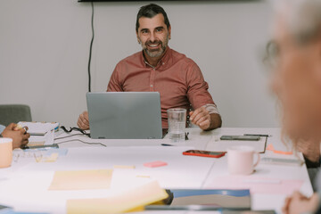 A handsome middle-aged man talking and smiling to his colleagues