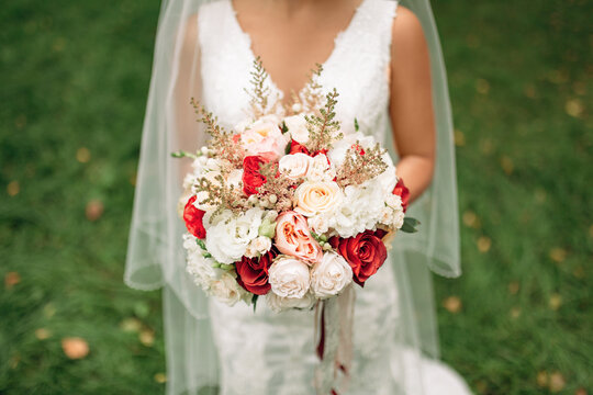 A close-up photo of the bride's luxury bouquet. A large bouquet of fresh white and red flowers in the hands of the bride. Wedding decor and details