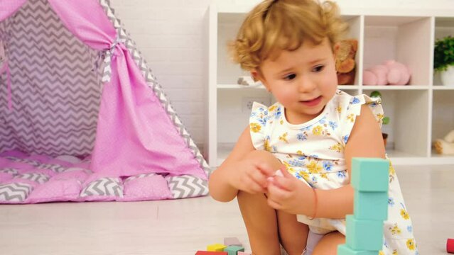 The child plays in the children's room with a wooden constructor. Selective focus.