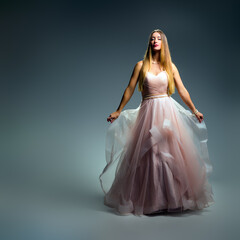Elegant fashion. Stunning woman in elegant long dress in studio. Luxury evening fashion. Glamour...