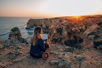 Female Traveler Enjoys Sunset View of Marinha Beach in Algarve, Portugal from Cliff in Lagoa