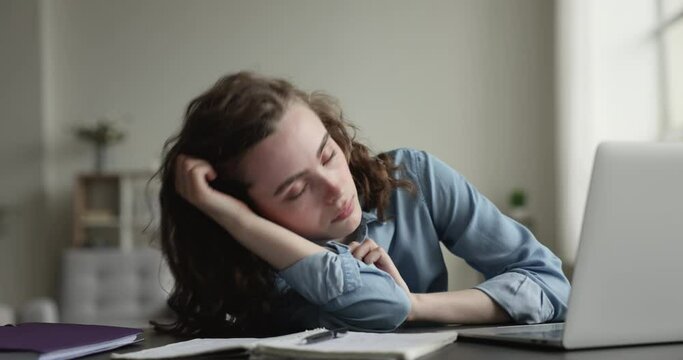 Young employee or student woman sits at desk falls asleep during making bored assignment, no motivation to work, feels exhaustion due to overtime job or information overload, need rest, lack of sleep