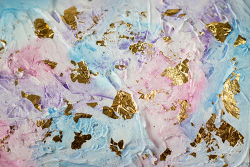 Textured pastel voluminous background in pink, blue, purple with torn off pieces of gold glued on. Close-up