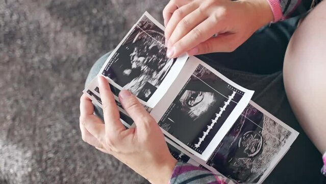 Happy pregnant woman holding ultrasound scan pictures of her baby gender reveal, medical testing and examination before childbirth. Happy pregnancy of young mom, pregnant belly and motherhood concept