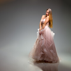 Elegant fashion. Stunning woman in elegant long dress in studio. Luxury evening fashion. Glamour...