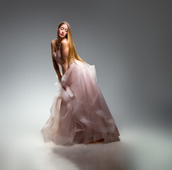 Elegant fashion. Stunning woman in elegant long dress in studio. Luxury evening fashion. Glamour...