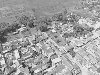 Fototapeta premium A black and white photo with a contrast between dense settlements and large rice fields in the Bandung area - Indonesia.