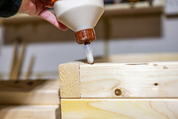 applying wood glue to the bed joint of a timber lumber planter box in the workshop