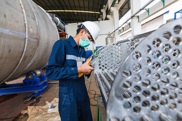 Male worker inspecting surface on heat exchanger, tube bundle industrial construction warehouse...