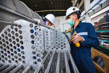 Male worker inspecting surface on heat exchanger, tube bundle industrial construction warehouse positive