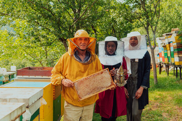 Arab woman investitors with an experienced senior beekeeper checking the quality and production of honey at a large bee farm
