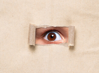 Man looking through torn paper hole. Man peeking from behind the torn.