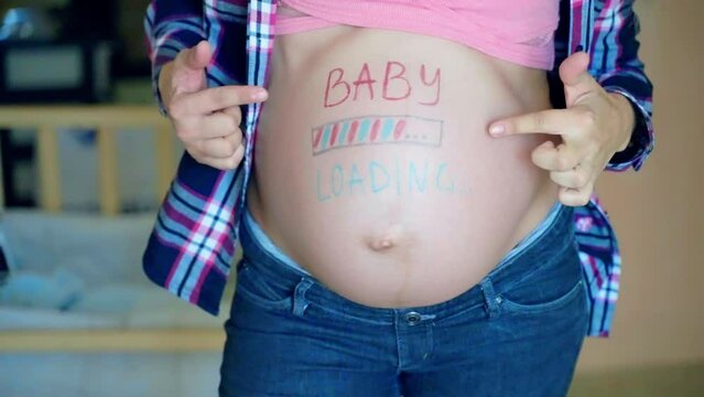 Blue and pink baby loading inscription on woman's pregnant belly, expecting mom waiting for her baby arrival, happy female stroking gently her pregnant belly, tenderness and motherhood concept