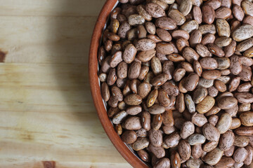 Dry Pinto Beans in Clay Bowl With Wooden Spoon in Rustic Kitchen