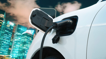 Electric vehicle, EV car recharges battery energy at charging station on the freeway in urban area...