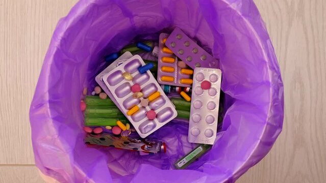 throws medicine pills into the trash.