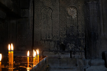 burning candles on candlestick in old stone church, dark blurred abstract background. Religious,...