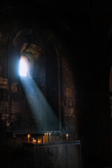 Interior of ancient church. burning candles on candlestick in old stone monastery, dark blurred...