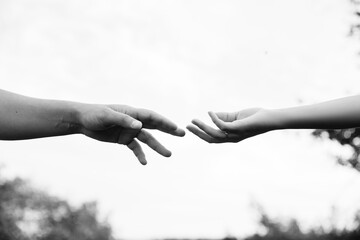 A close-up photo of the hands of a couple in love going in different directions. Fingers touching each other. Isolated hands touching