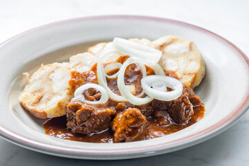 beef goulash with onion rings and dumplings