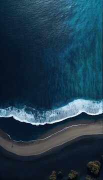 Beautiful aerial shot of a dark beach, dark blue water. Top shot of a shore scene with a drone