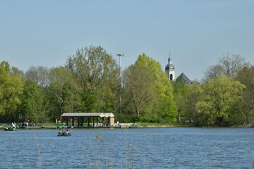 Le grand étang avec son embarcadère des pédalos et le clocher de l'église de l'abbaye de Vlierbeek émergeant des arbres du domaine provincial de Kessel-Lo au nord de Louvain 