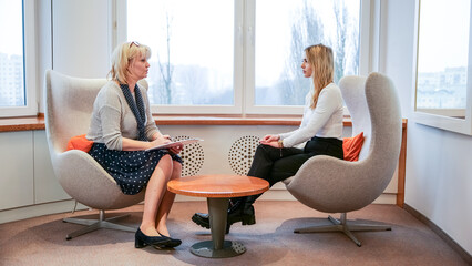 Two women of different generations are talking at a business meeting in an elegant office
