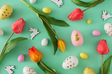 Fototapeta na wymiar Easter concept. Top view photo of yellow white pink eggs easter bunnies red tulips on isolated teal background