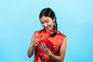 girl wearing cheongsam on chinese new year counting the large amount of money in the red envelope received as a New Year's gift and his face looked happy. Indoor studio isolated on blue background