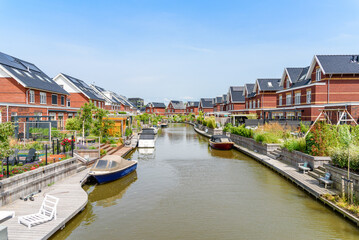 Modern energy efficient brick houses with rooftop solar panels along a canal in the Netherlands on...