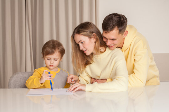Cheerful smiling family, parents in yellow clothes, mom and dad with son painting