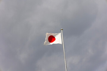 曇り空と風に靡く日の丸の旗