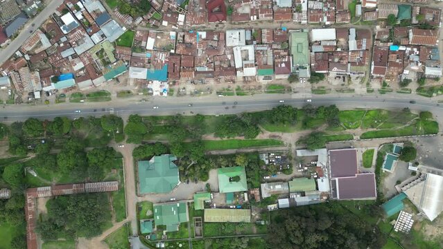 Aerial view of Mbeya city in Tanzania, Africa. Town is located in south west of Tanzania. Narrow highland valley surrounded by a bowl of high mountains. Slum and greenery separated by highway.
