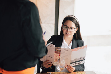 Executive woman placing the order in a restaurant. A smiling Latina woman dictating the order to the waiter of a fancy 