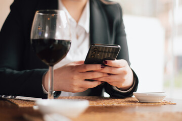 Hands of a white woman typing on a cell phone inside a fancy restaurant. Hands of an executive...