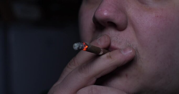 A man inhales the poisonous smoke of a cigarette. People's nicotine addiction is a deadly habit. Close-up man smokes a cigarette.