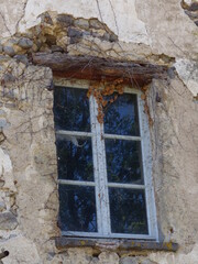 fenêtre ancienne d'un vieux bâtiment abandonné avec ses carreaux reflétant les arbres avoisinant par une belle journée printanière