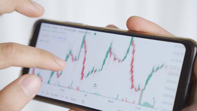 Close-up male hands searching and analyzing stock market data. 
Trader, financial investor close-up hands looking at charts on phone and analyzing them.
