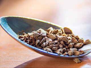 a spoon full of instant coffee extreme close up on a wooden table