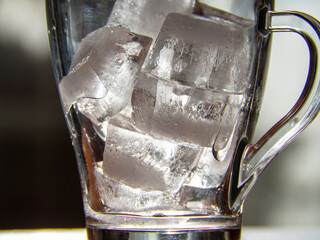 a glass with ice cubes in it sitting on a table