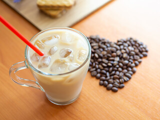 a cup of coffee with ice and a red straw next to a heart shaped pile of coffee beans, cookies on...
