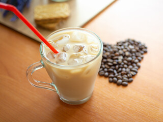 a cup of coffee with ice and a red straw next to a heart shaped pile of coffee beans, cookies on...