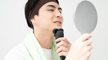 メンズ美容　鏡を見ながら髭を剃る男性