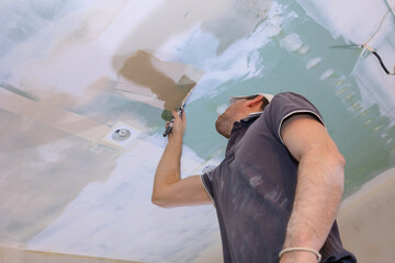 Worker make repairs in new apartment. Man plaster walls and ceilings. High quality photo