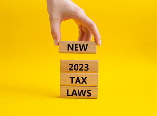 New 2023 Tax Law symbol. Wooden blocks with words New 2023 Tax Law. Beautiful yellow background....