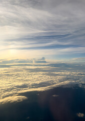 Fototapeta na wymiar Sunrise above clouds from airplane window
