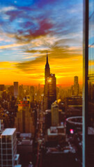 A Mesmerizing Sunrise View from Above the Skyline" - As the sun rises over the city that never sleeps, the iconic New York City skyline comes to life with a mesmerizing blend of warm colors and striki